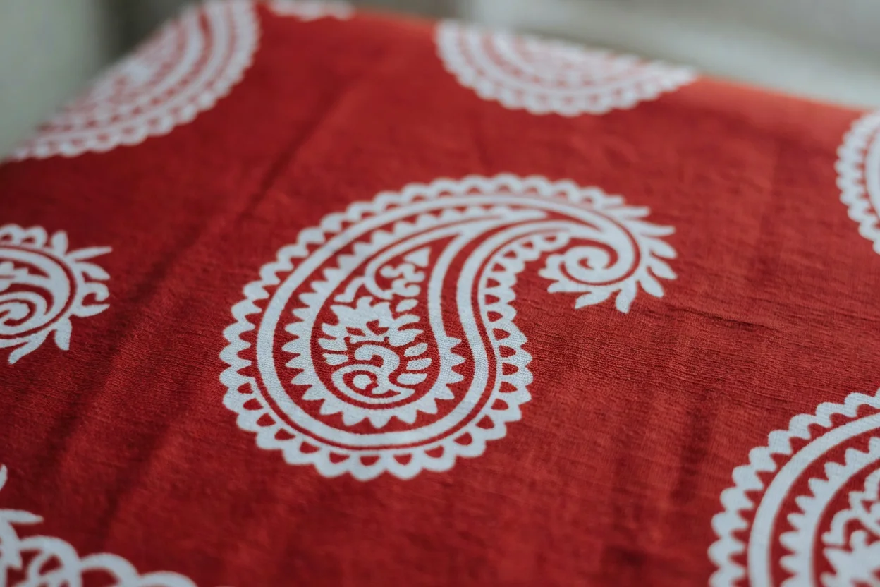 Un bandana en coton bordeaux à motif paisley déployé à plat, coin relevé montrant l'envers